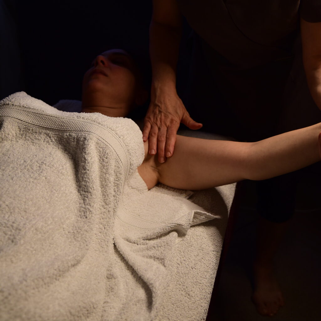 Therapist performing manual lymphatic drainage by gently massaging the lymph nodes under a client's armpit