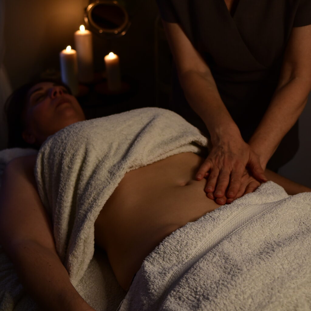 Therapist performing manual lymphatic drainage with gentle movements on a client's abdomen